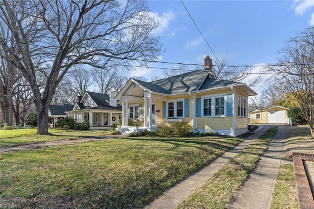 bungalow featuring a porch, a chimney, and a front yard