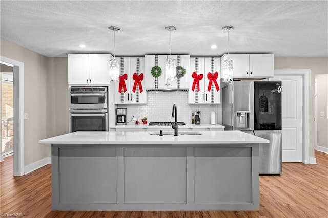 kitchen featuring a center island with sink, white cabinetry, and light hardwood / wood-style floors