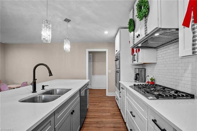 kitchen with pendant lighting, white cabinets, sink, dark hardwood / wood-style floors, and stainless steel appliances