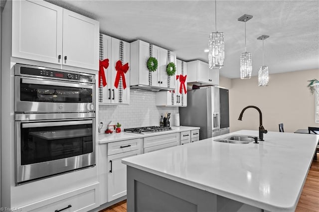 kitchen featuring white cabinets, sink, light hardwood / wood-style flooring, an island with sink, and stainless steel appliances