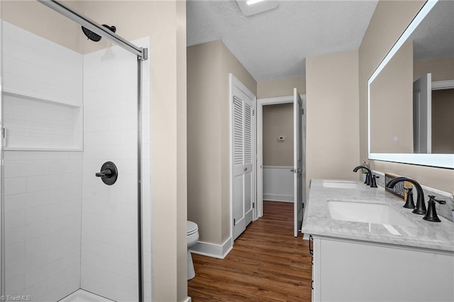 bathroom with vanity, toilet, a textured ceiling, walk in shower, and wood-type flooring