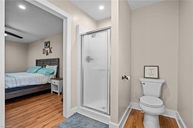 bathroom with hardwood / wood-style flooring, a shower with door, and ceiling fan