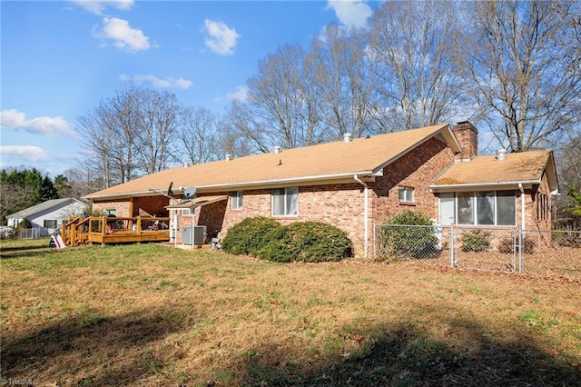 rear view of property featuring a lawn, a wooden deck, and central AC unit