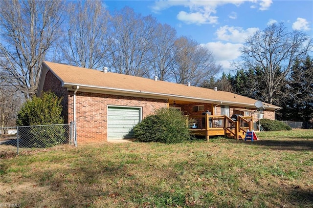 rear view of property featuring a garage, a deck, and a lawn