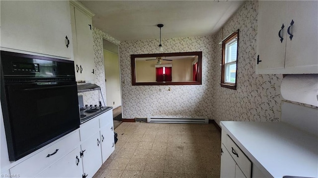 2308 Sprague St, Winston-Salem, NC 27107 - kitchen with black oven, a baseboard radiator, wallpapered walls, light flooring, and white cabinetry