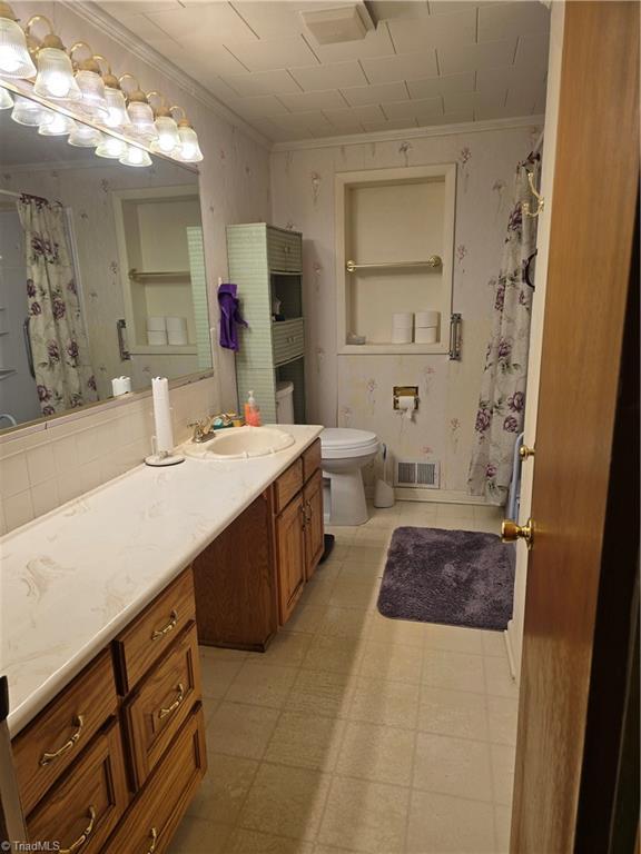 210 Grinton Ave, Wilkesboro, NC 28697 - full bath with ornamental molding, vanity, toilet, a shower with curtain, and tile patterned floors