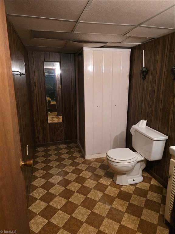 210 Grinton Ave, Wilkesboro, NC 28697 - bathroom with wood walls, toilet, tile patterned floors, and a paneled ceiling