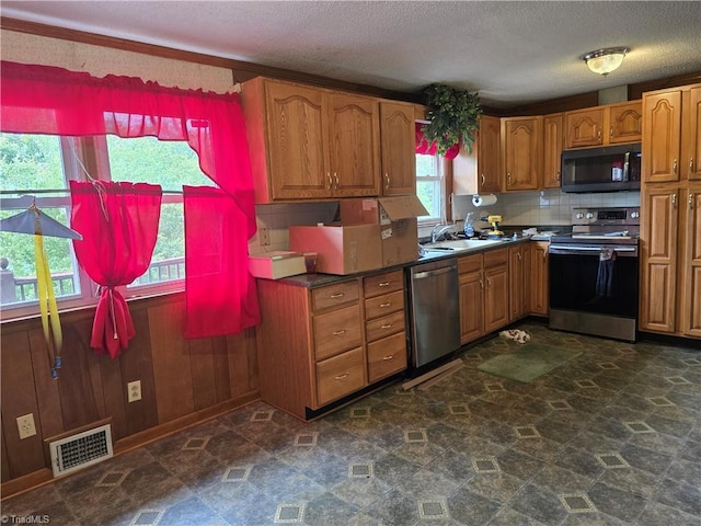 210 Grinton Ave, Wilkesboro, NC 28697 - kitchen with appliances with stainless steel finishes, brown cabinets, a textured ceiling, a sink, and dark stone finish flooring
