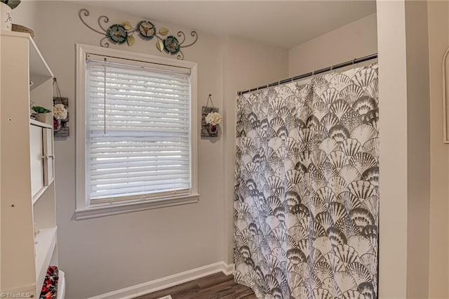 bathroom featuring a shower with shower curtain, baseboards, and wood finished floors