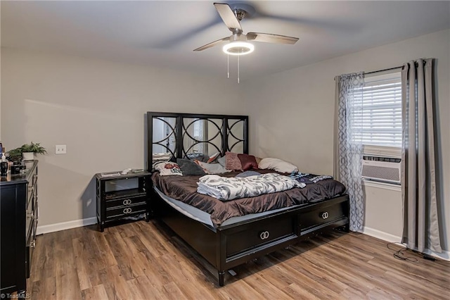 bedroom with baseboards, ceiling fan, wood finished floors, and cooling unit