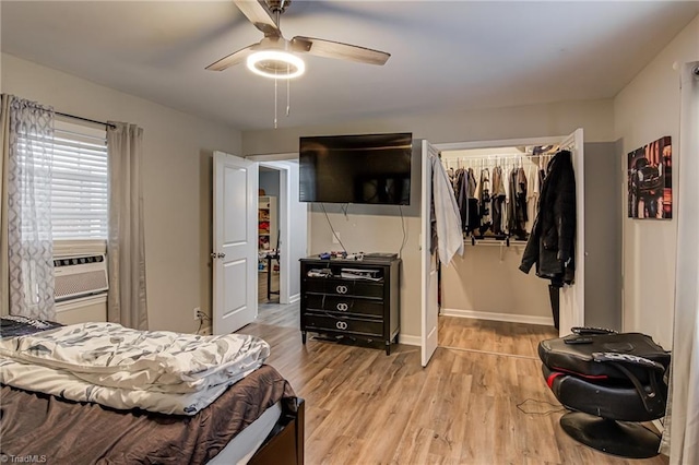 bedroom with a walk in closet, a ceiling fan, baseboards, wood finished floors, and a closet