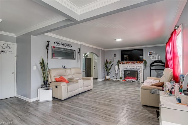 living room with arched walkways, baseboards, ornamental molding, and wood finished floors