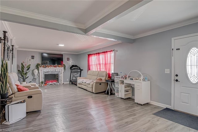 foyer with a fireplace with raised hearth, baseboards, ornamental molding, and light wood finished floors