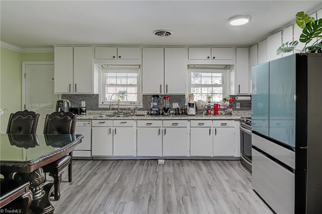kitchen featuring freestanding refrigerator, decorative backsplash, a sink, and plenty of natural light