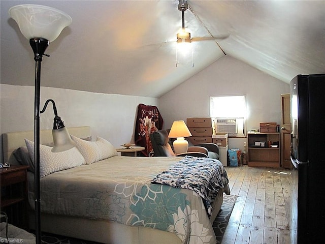 bedroom with hardwood / wood-style flooring, freestanding refrigerator, cooling unit, ceiling fan, and vaulted ceiling