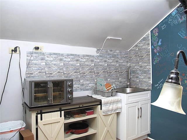 kitchen with white cabinetry, a toaster, and a sink