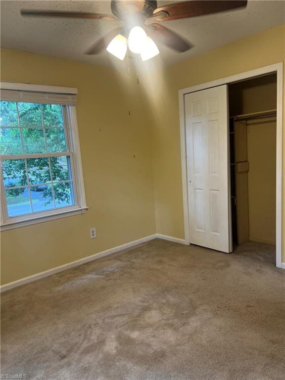 unfurnished bedroom featuring a closet, ceiling fan, light colored carpet, and a textured ceiling