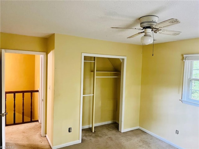 unfurnished bedroom with a textured ceiling, ceiling fan, light colored carpet, and a closet