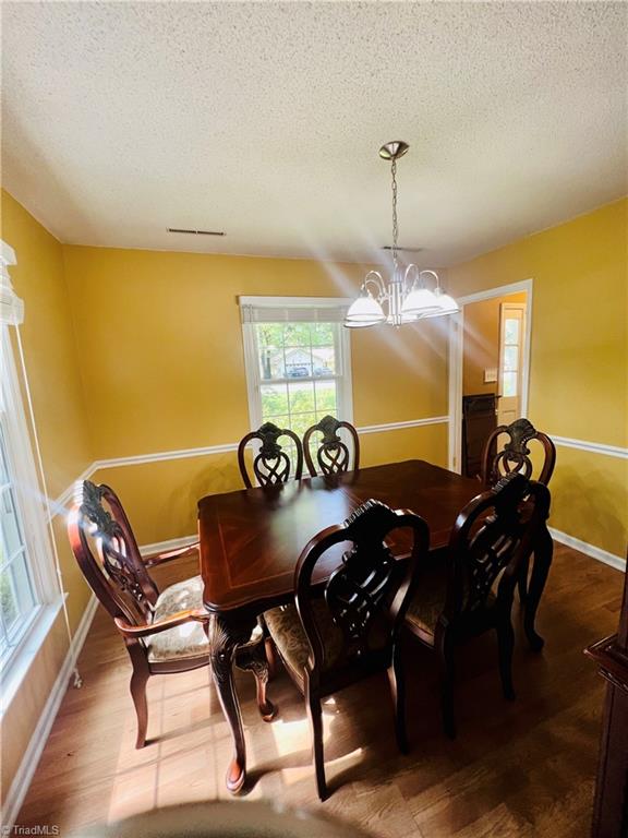 dining space featuring an inviting chandelier, a textured ceiling, and hardwood / wood-style flooring