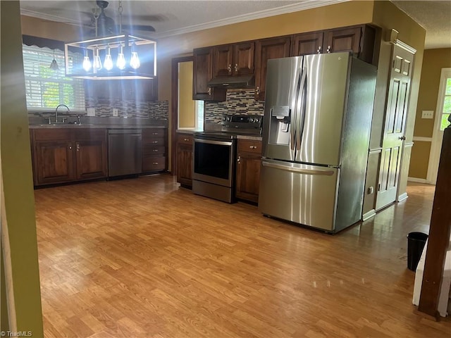 kitchen featuring light wood-type flooring, decorative backsplash, stainless steel appliances, ornamental molding, and ceiling fan