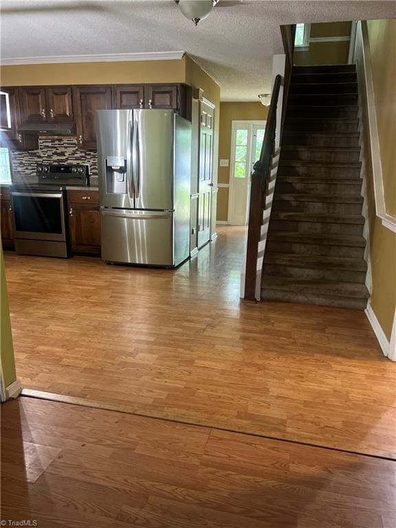 kitchen featuring stainless steel appliances, backsplash, dark brown cabinetry, and light wood-type flooring