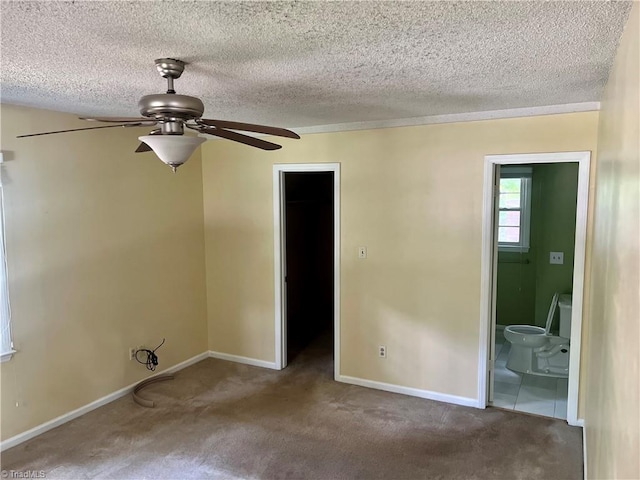 unfurnished bedroom featuring ceiling fan, carpet floors, ensuite bath, and a spacious closet