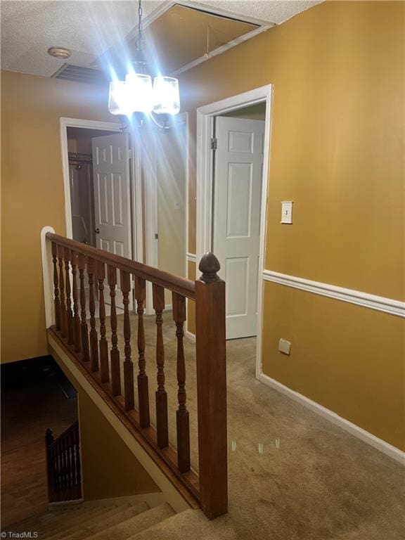 stairs featuring a textured ceiling and carpet