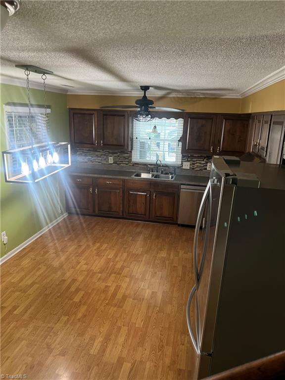 kitchen featuring sink, light hardwood / wood-style flooring, stainless steel appliances, crown molding, and ceiling fan