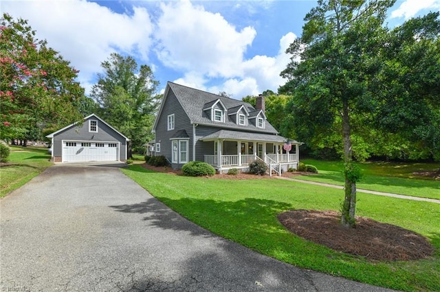 new england style home featuring an outdoor structure, a garage, a front yard, and covered porch