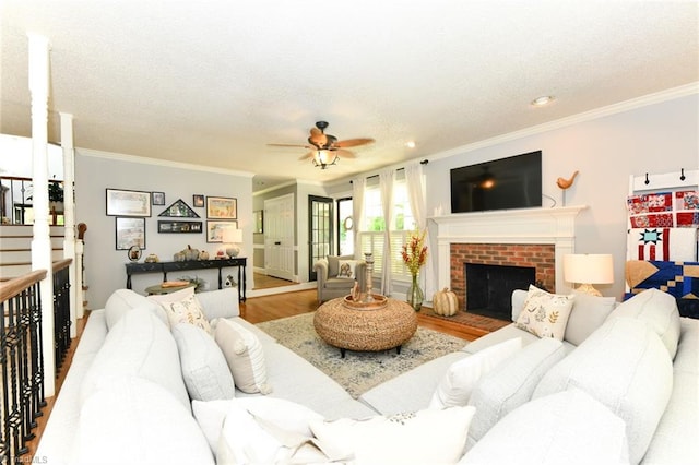 living room with crown molding, light hardwood / wood-style flooring, ceiling fan, and a fireplace