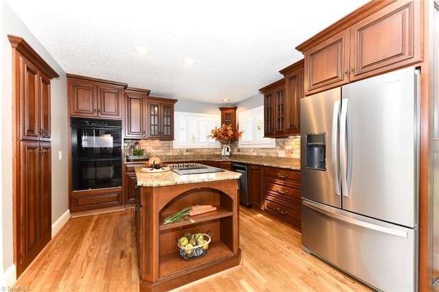 kitchen featuring appliances with stainless steel finishes, tasteful backsplash, a center island, and light hardwood / wood-style floors