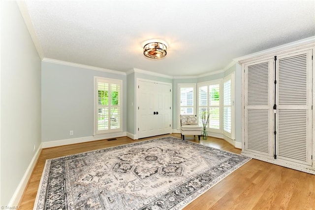 living area featuring a textured ceiling, ornamental molding, and light hardwood / wood-style floors