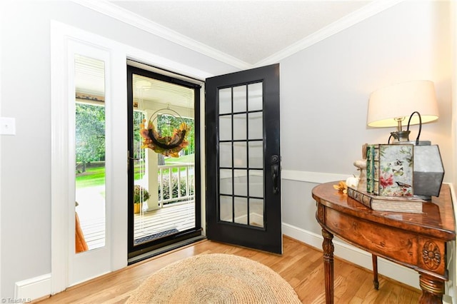 entrance foyer with ornamental molding, light hardwood / wood-style flooring, and a wealth of natural light