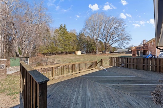 wooden terrace featuring a storage unit and a yard