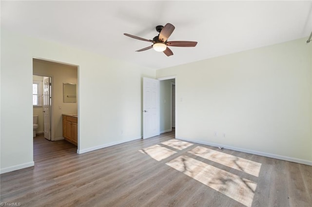 unfurnished bedroom with light wood-type flooring, connected bathroom, and ceiling fan