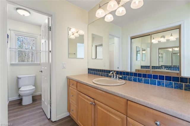 bathroom with toilet, wood-type flooring, vanity, and decorative backsplash