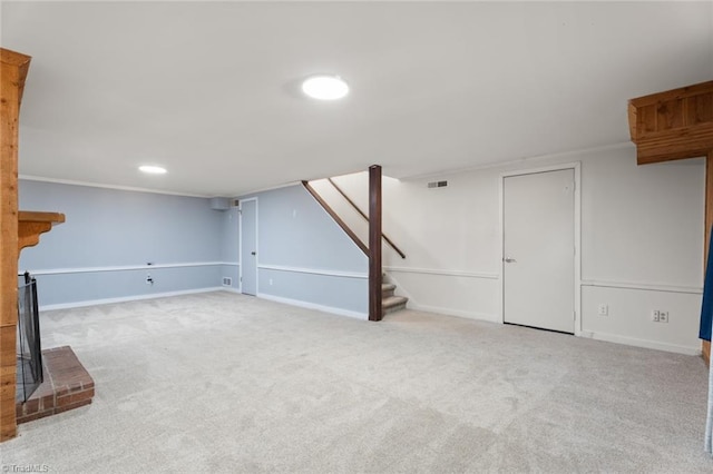 basement with ornamental molding, light colored carpet, and a fireplace