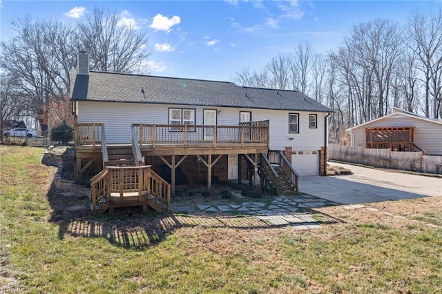 rear view of property featuring a garage, a deck, and a lawn