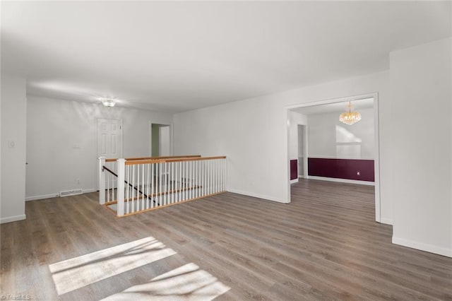 empty room featuring a notable chandelier and dark hardwood / wood-style flooring