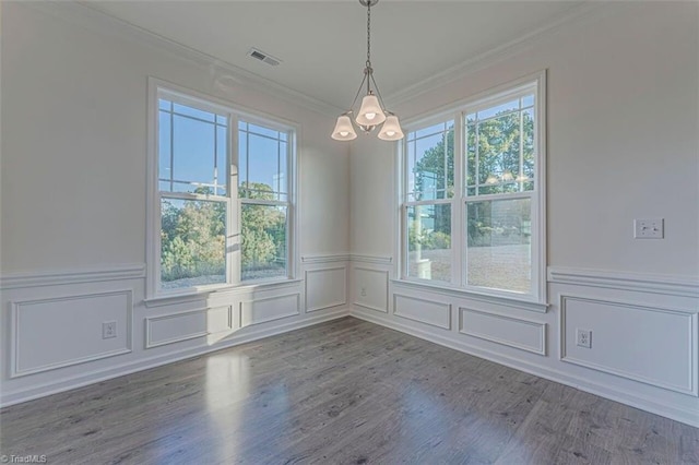 unfurnished dining area with dark hardwood / wood-style flooring, crown molding, a notable chandelier, and a wealth of natural light