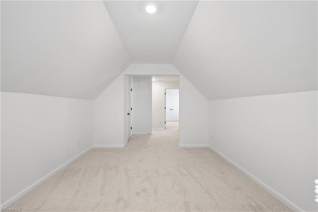 bonus room featuring vaulted ceiling and light colored carpet