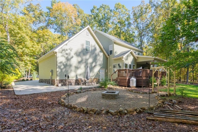 rear view of house with a wooden deck, an outdoor fire pit, and a patio area