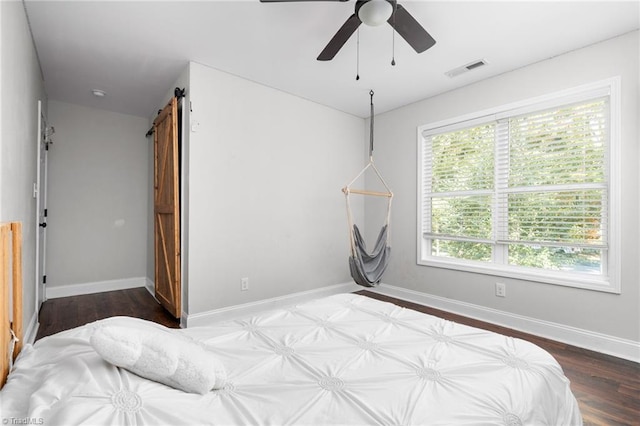 bedroom featuring hardwood / wood-style flooring, a barn door, and ceiling fan