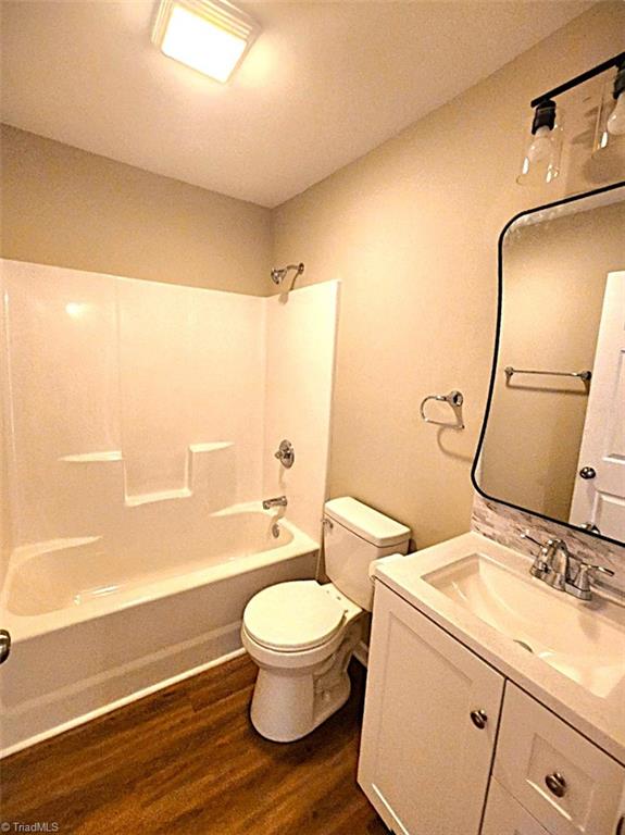 full bathroom with hardwood / wood-style floors, vanity, shower / bath combination, and toilet