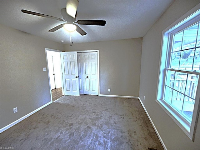 unfurnished bedroom with carpet flooring, ceiling fan, a closet, and a textured ceiling