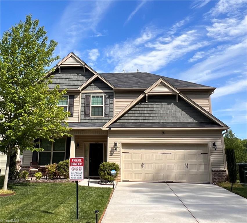 craftsman-style home featuring concrete driveway, a front lawn, and a garage