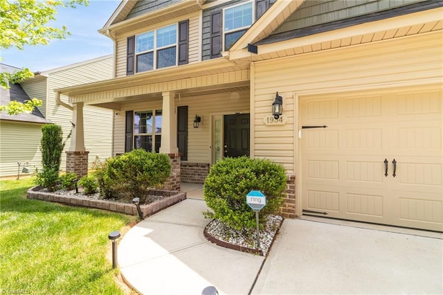 1934 Rubywood St, Greensboro, NC 27405 - view of exterior entry featuring covered porch, brick siding, driveway, and a garage