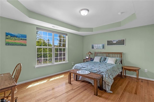 1934 Rubywood St, Greensboro, NC 27405 - bedroom featuring baseboards, a tray ceiling, wood finished floors, and visible vents