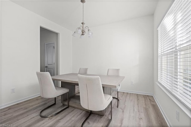 dining area featuring light wood-type flooring and a notable chandelier