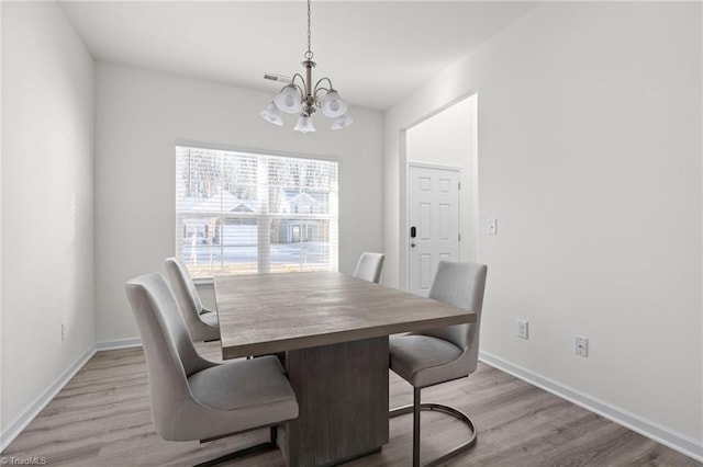 dining area featuring light hardwood / wood-style floors and an inviting chandelier